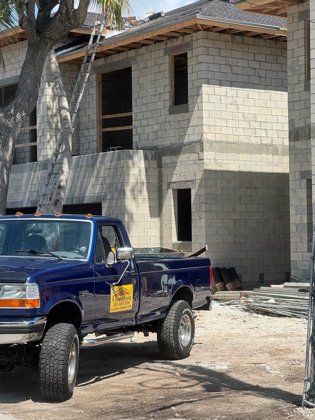 A pickup parked at a block house going up.